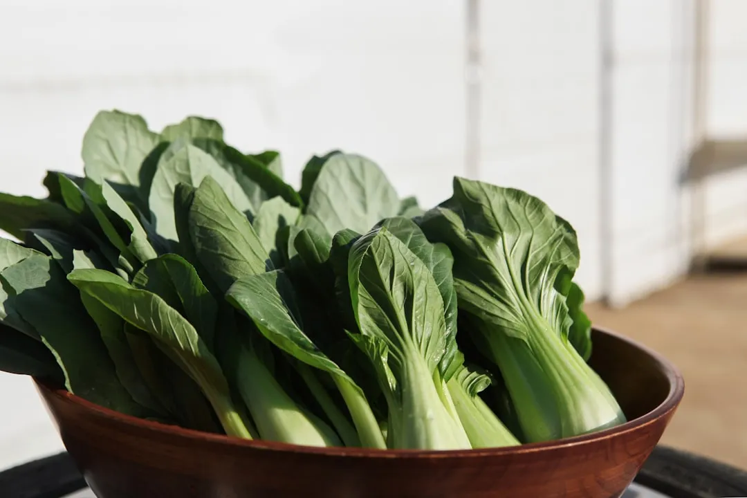 a wooden bowl filled with green leafy vegetables