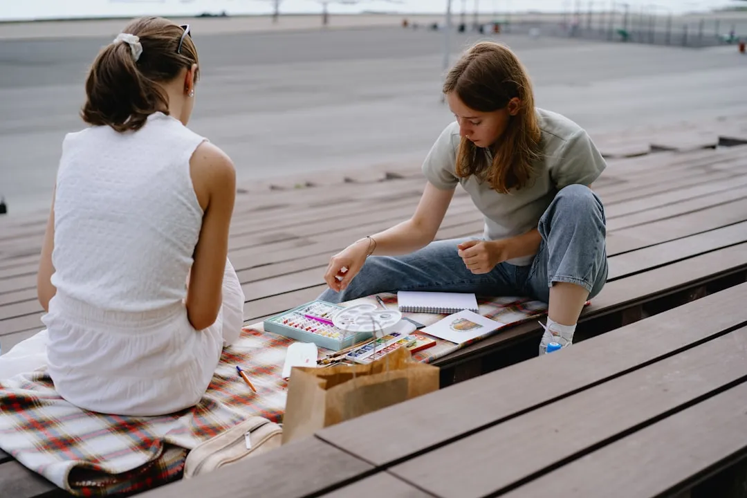 A couple of women sitting on top of a picnic table