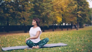 Woman meditating on a yoga mat in autumn park.