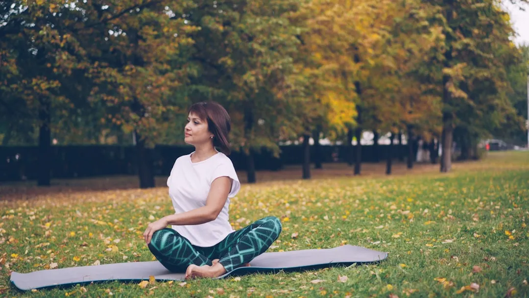Woman meditating on a yoga mat in autumn park.