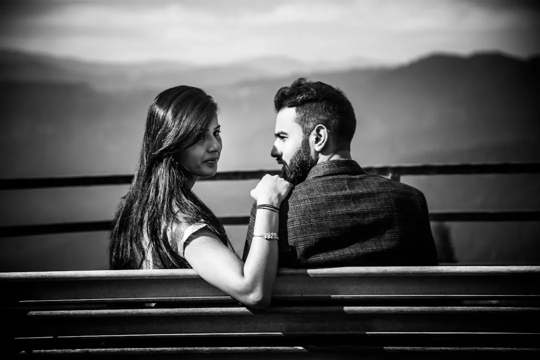 a black and white photo of a couple sitting on a bench