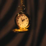 A gold pocket watch hanging from a chain