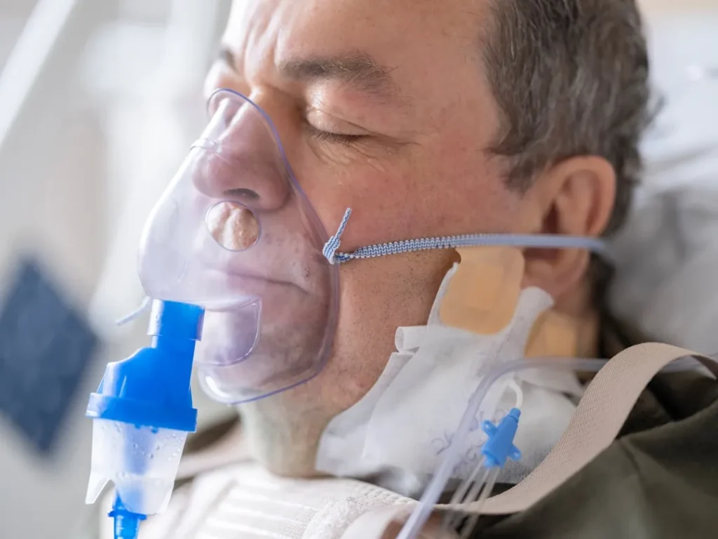 a man laying in a hospital bed with an oxygen tube attached to his face