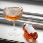 a bottle of alcohol sitting next to a wine glass