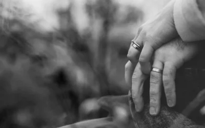grayscale photo of two person holding hands with wedding rings