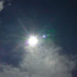 The bright sun shines through cloudy skies.