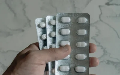 Hand holding blister packs of white pills