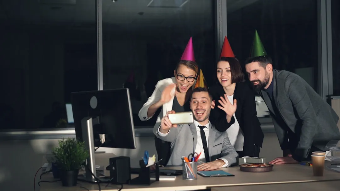 Colleagues celebrating with party hats taking a selfie.
