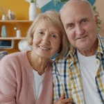 Elderly couple smiling together on a couch.