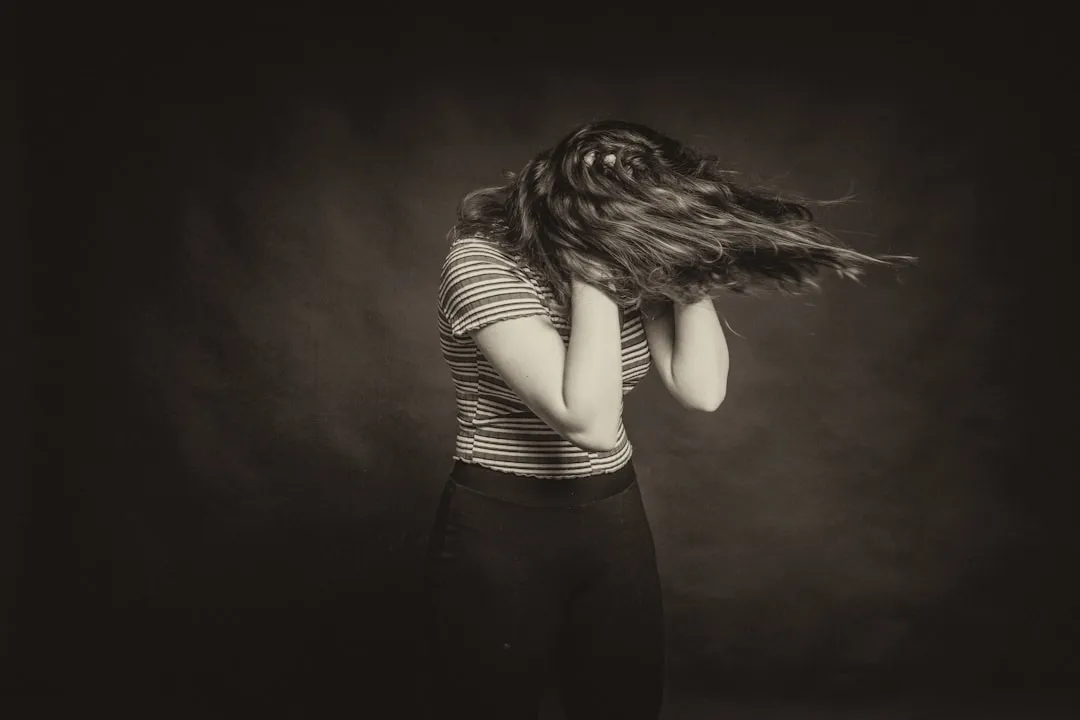 woman in black and white striped long sleeve shirt covering her face with hair