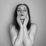 a black and white photo of a woman with her hands on her face