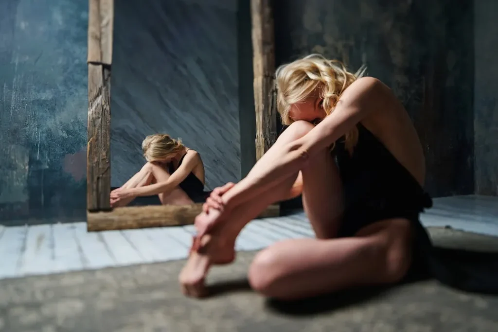 a woman sitting on the floor in front of a mirror