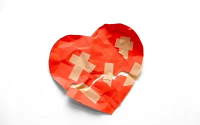 A broken red heart taped together on white background