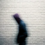 a blurry image of a person standing in front of a brick wall