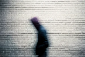 a blurry image of a person standing in front of a brick wall