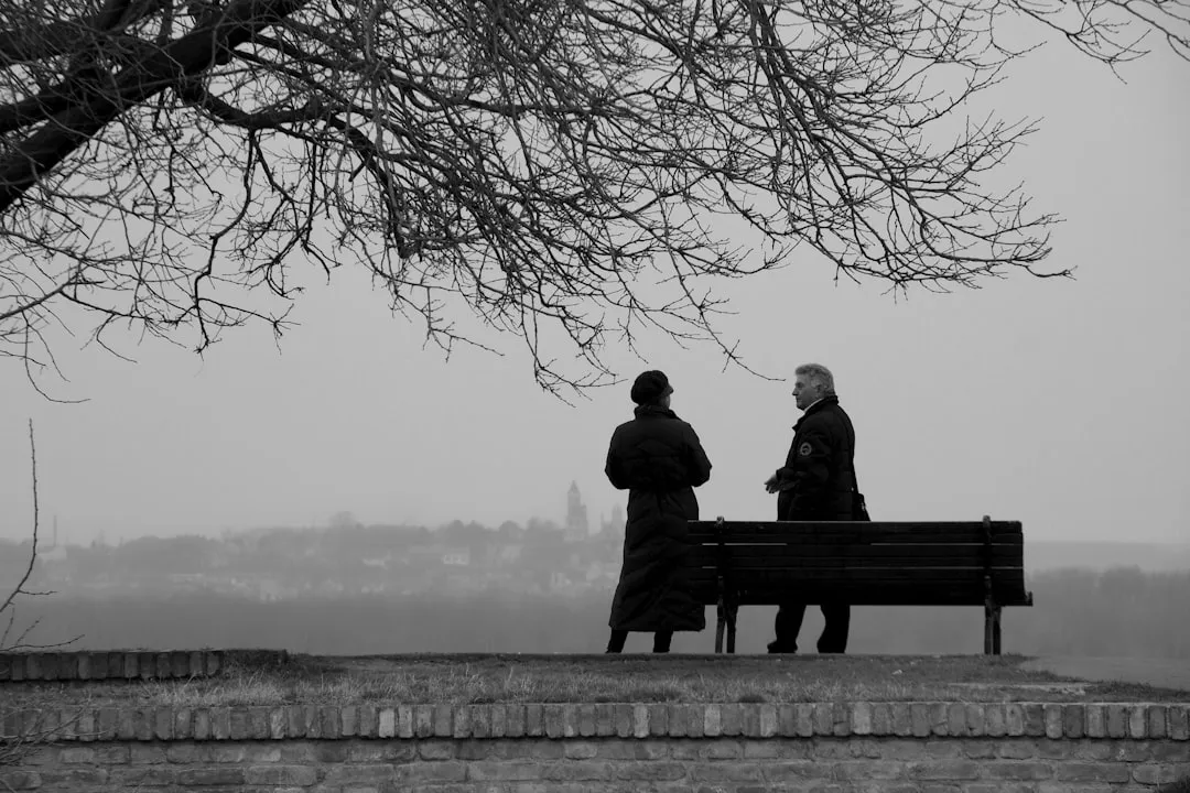 man and woman sitting on bench near body of water during daytime