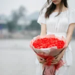 a woman holding a bouquet of red roses