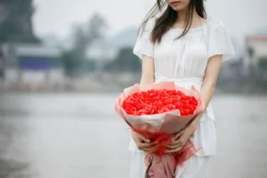 a woman holding a bouquet of red roses