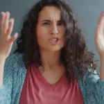 Woman with curly hair looking angry and frustrated.