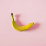 A single banana on a pink background