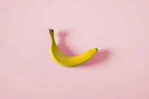 A single banana on a pink background