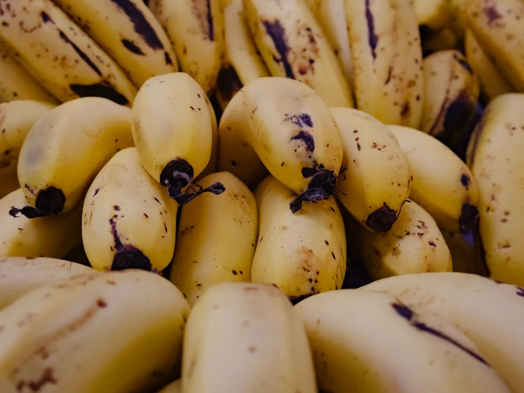 A pile of ripe yellow bananas with brown spots.