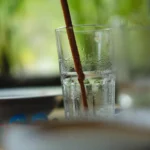 a close up of a glass of water with a straw sticking out of it