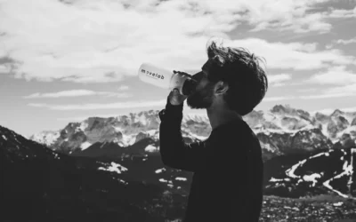 man drinking water on top of mountian