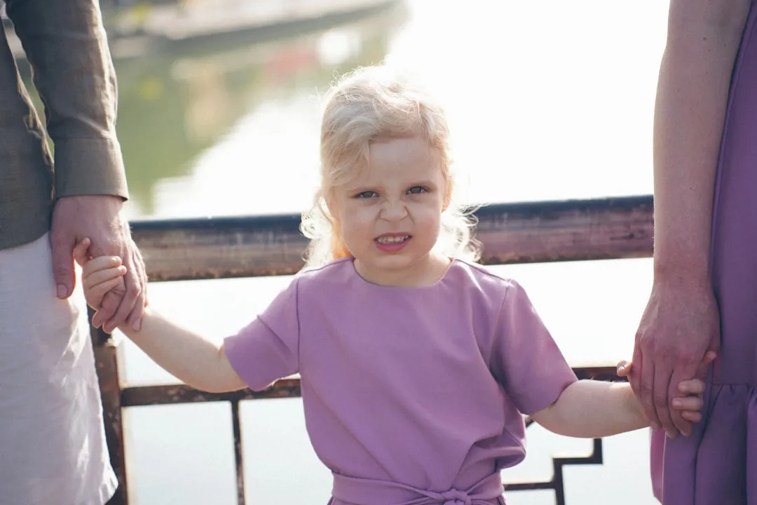Young girl holding hands with adults outdoors