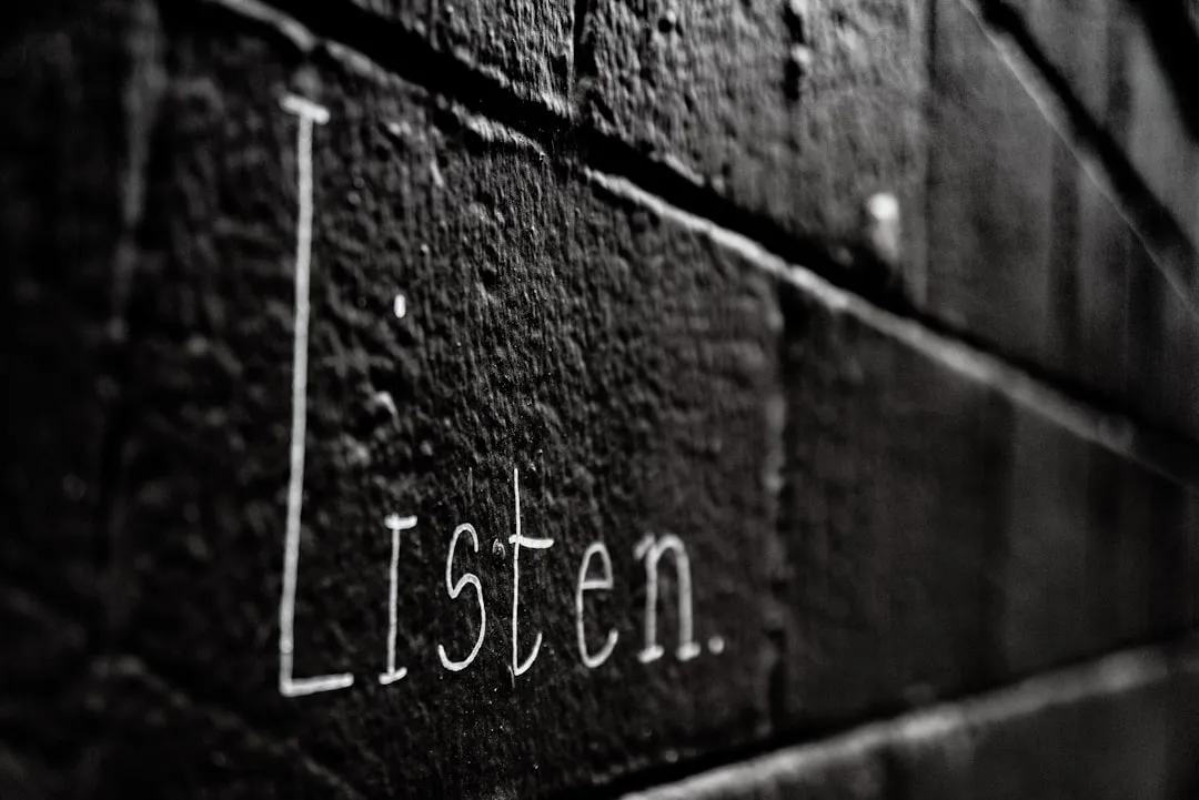 a black and white photo of the word listen written on a brick wall