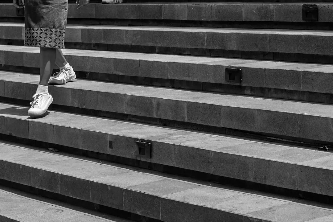 Person walking down stone stairs in black and white