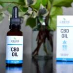 a bottle of cbd oil next to a vase of flowers