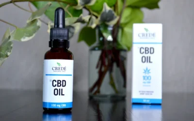 a bottle of cbd oil next to a vase of flowers