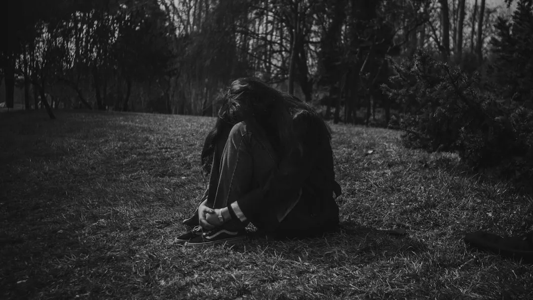 A person sitting alone in a dark, grassy park.