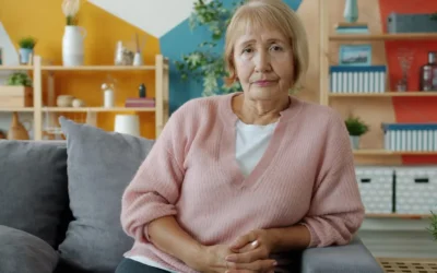 Elderly woman sitting on a couch in a living room.