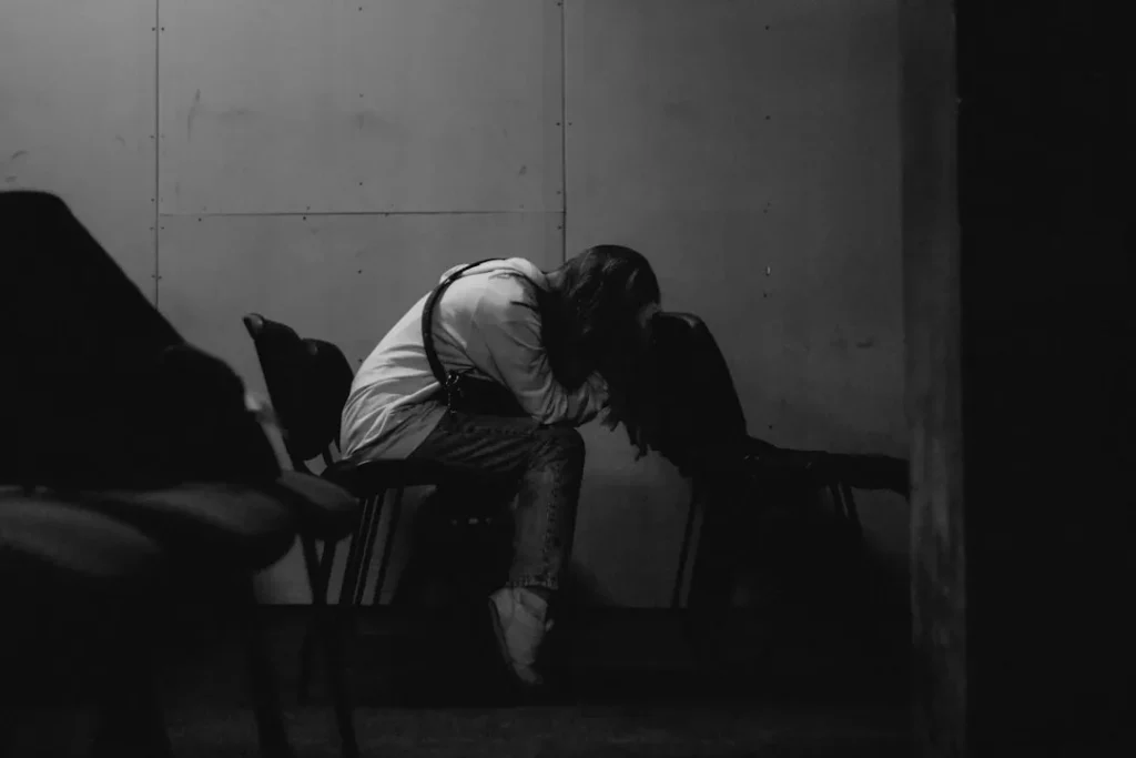 A person sits alone, head in hands.