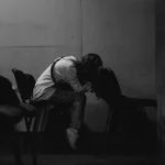 A person sits alone, head in hands.