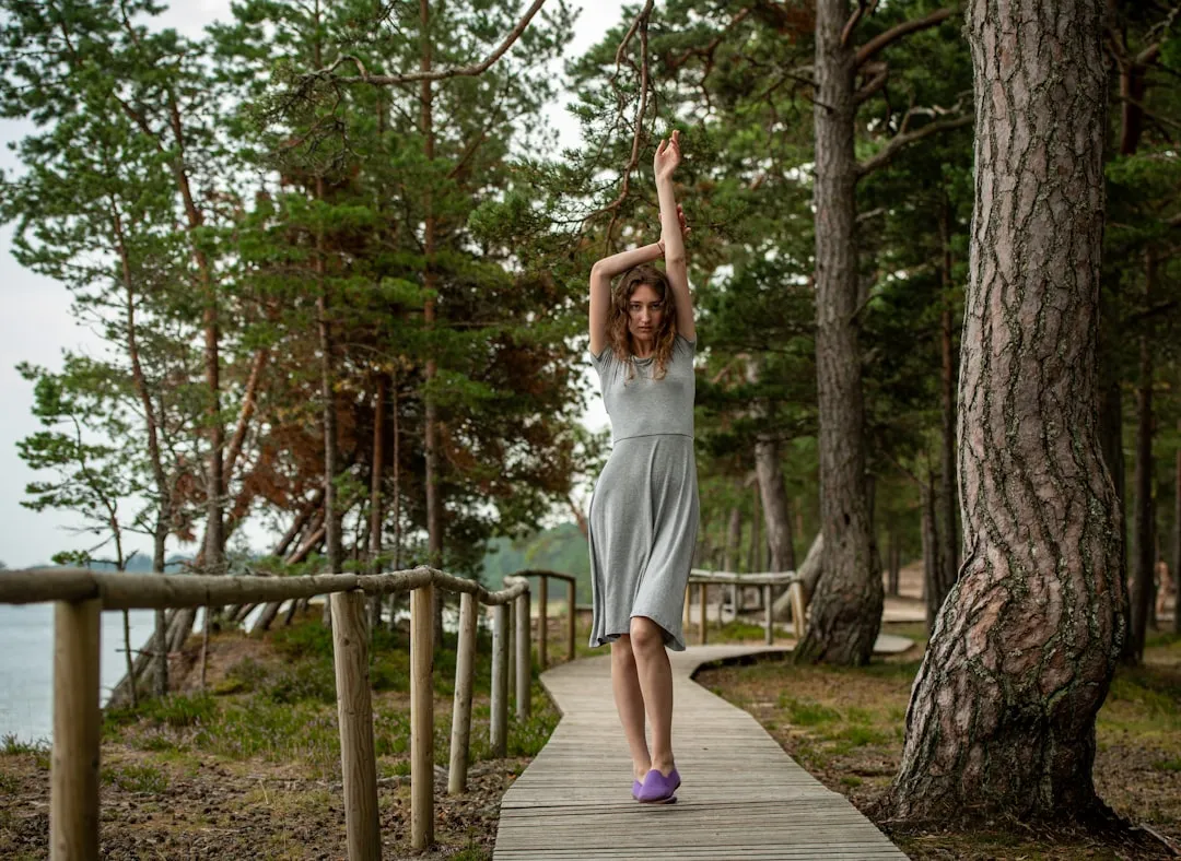 Woman in grey dress walks on boardwalk in forest
