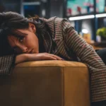 a woman sitting on a couch with her head on her hand