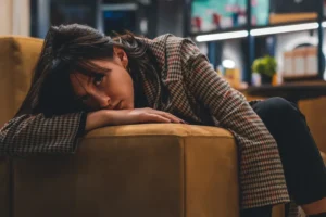 a woman sitting on a couch with her head on her hand