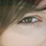 a close up of a person's eye with long hair
