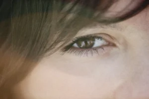a close up of a person's eye with long hair