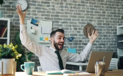 a man sitting at a desk with his arms in the air