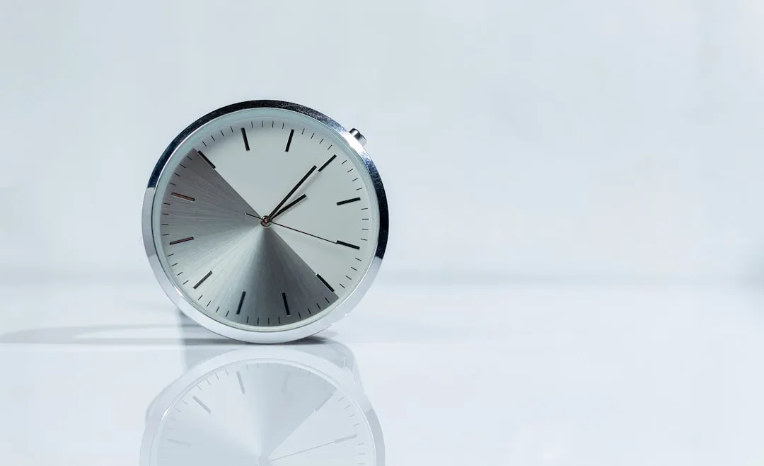 A silver clock reflects on a glossy surface.