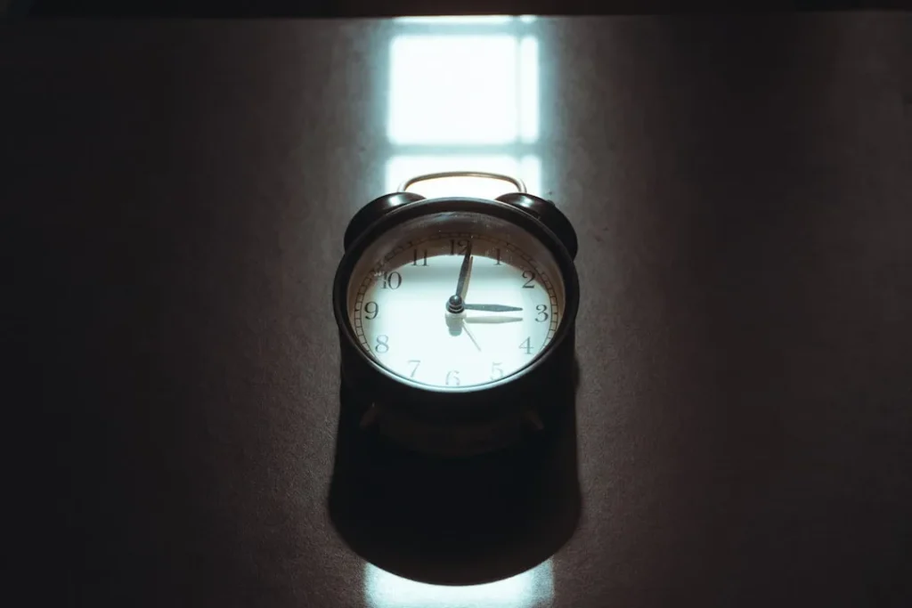 Retro alarm clock on a dark reflective surface.