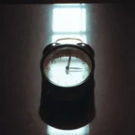 Retro alarm clock on a dark reflective surface.