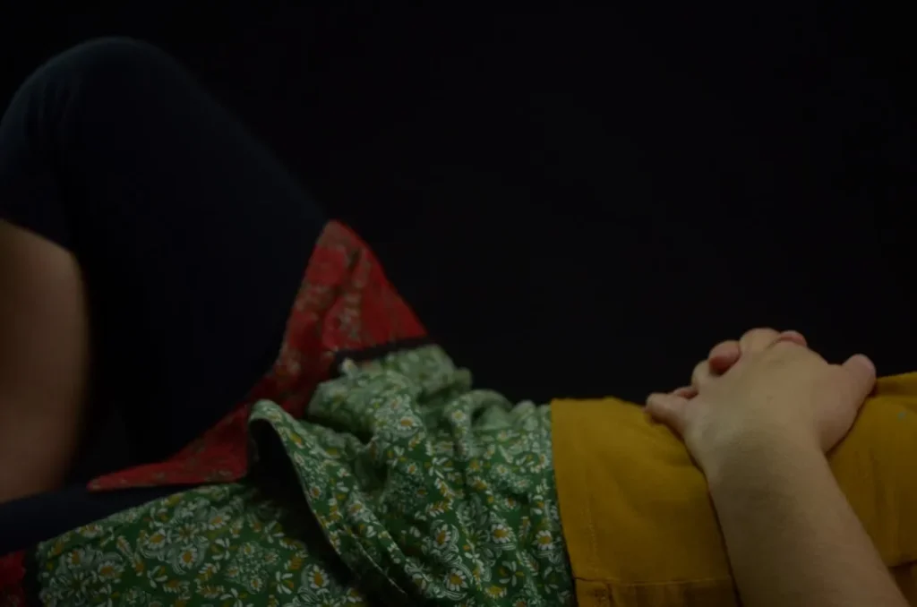 person lying on bed with hands on stomach