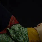 person lying on bed with hands on stomach
