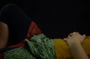 person lying on bed with hands on stomach
