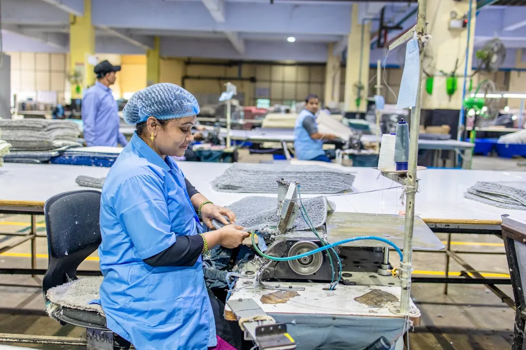 Factory worker sews with a machine on a production line.
